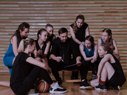 The coach's dynamic interaction with the team in this huddle illustrates the blend of transformational and transactional leadership styles that drive both inspiration and disciplined execution