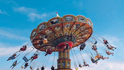 People enjoying a ride on a carousel at a theme park during the daytime