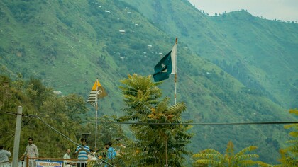 Pakistani and Azad Kashmir flags wave against the lush green hills of Kashmir amid renewed India-Pakistan tensions following the Pahalgam attack