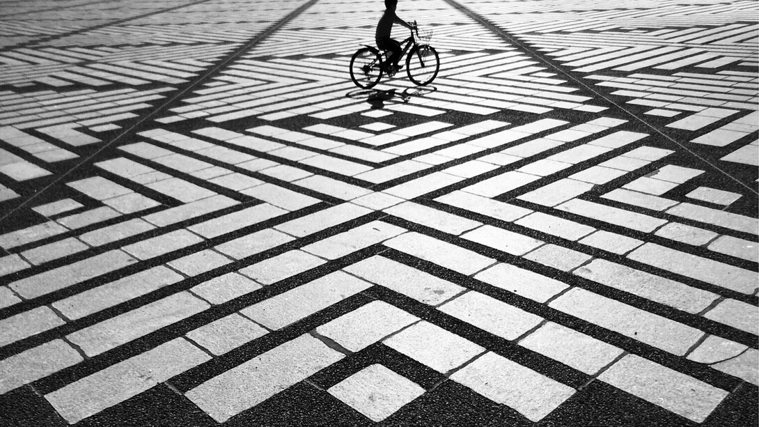 Un niño en bicicleta en una plaza desierta