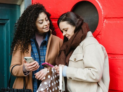 Two people standing together using mobile phones