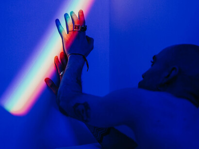 A shirtless man seeks solace in light