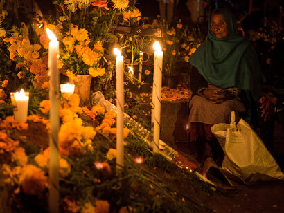 Mujer acompaña a sus difuntos durante el Día de Muertos en un cementerio de Oaxaca, México