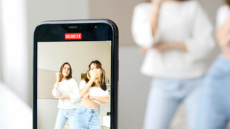 Jovens amigas dançam para vídeo no celular que depois será postado nas redes sociais 