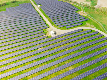 Aerial view of a grassy field in Germany, dotted with blue solar panels, capturing the blend of nature and renewable energy