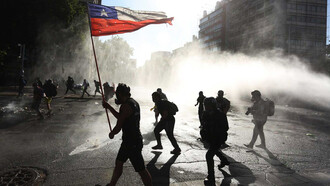 Ciudadanos chilenos entre el gas lacrimógeno en una protesta a favor de un cambio Constitucional en Chile