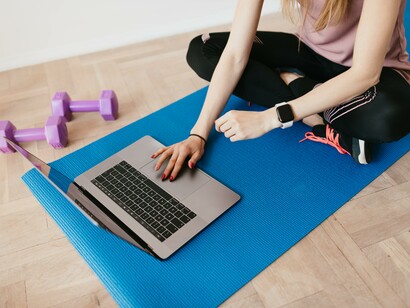 A person using a laptop whilst sitting on a yoga mat