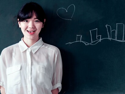 A student standing in front of a blackboard. Students need to take part in this process, they have to shape this world and leave their digital marks on it