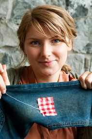 Woman repairing a pair of jeans using traditional visible mending techniques