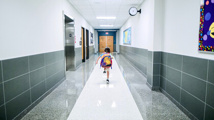 Criança percorrendo o corredor em direção a sala de aula de sua escola