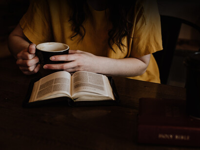 Mujer lee un libro mientras bebe una tasa de café