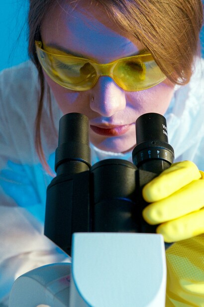 Uma mulher olhando através do microscópio