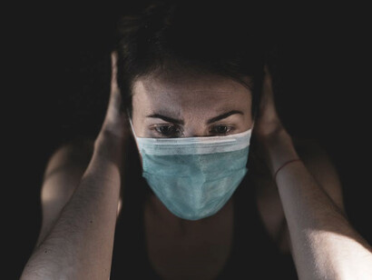 A woman wearing a mask during the pandemic, looking sad and depressed