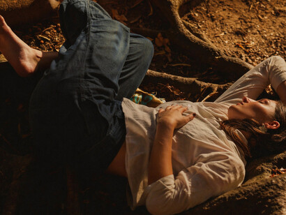Woman unwinding on the forest floor as sunlight filters through the tree
