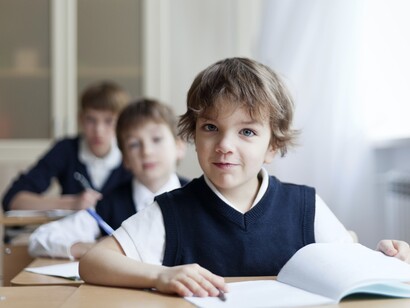 Niños de uniforme sentados en sus respectivos pupitres
