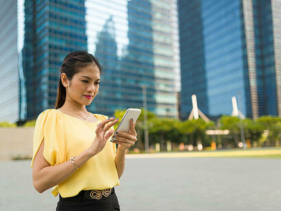 Asian woman reading text messages outdoors