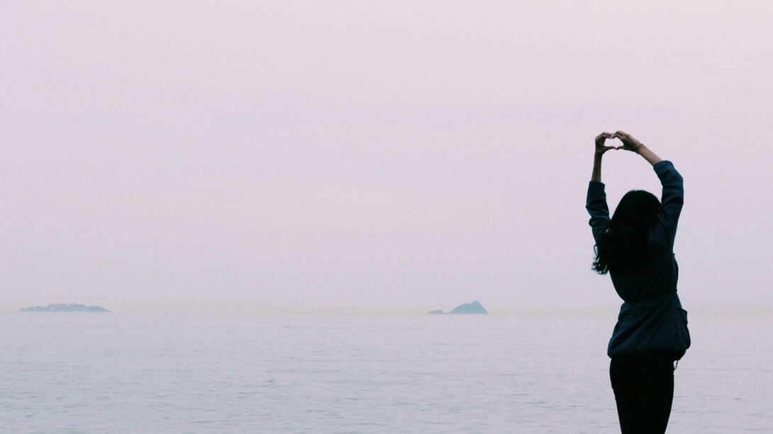 A woman in a peaceful setting is expressing her self-love to the world