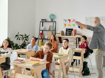 Professor orienta a turma diante de um quadro. Enquanto alguns acompanham, outros passam despercebidos por um sistema que prioriza avançar, não consolidar