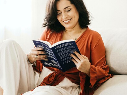 A woman lying on her bed enjoying the act of reading a book which she picked up from library