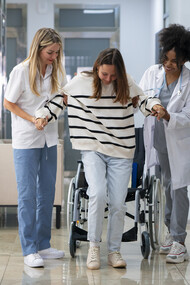 Female doctors assist a patient in a wheelchair with care and professionalism