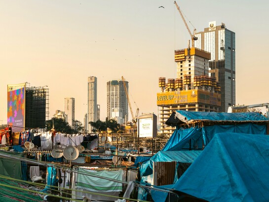 Makeshift homes in the shadow of modern high-rises, symbolizing the gap between economic success and social equality