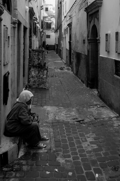 Essaouira's narrow alleys provide a tranquil setting for an elderly woman to cherish the city's legacy of unity and respect among Muslims, Jews, and Christians