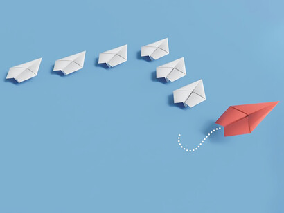 Convey the concept of individuality through a captivating image of paper planes, where a distinct red one stands apart from the rest in a symbolic representation of uniqueness and separation