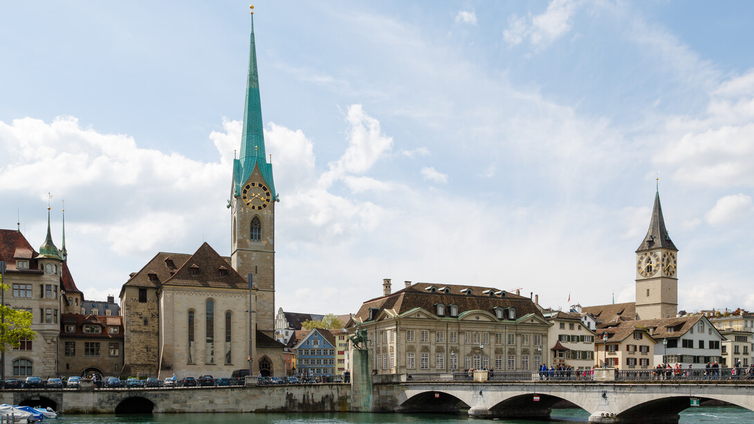 Zurich, Switzerland city view featuring Fraumünster Church, Zunfthaus zur Meisen, Münsterbrücke Bridge, and St. Peter Church in the historic Old Town skyline