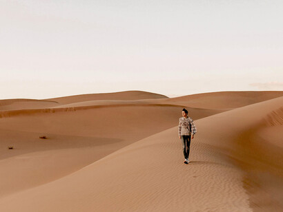 A solitary figure walking across a vast desert—silhouetted against an endless, open wilderness