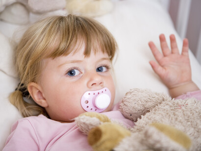 Una niña saluda con su chupete