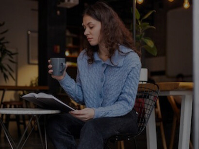 Woman unwinding in a cozy cafe, reading a book and savoring tea