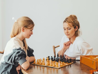 Mulher jogando xadrez com uma garota