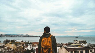 Homem contempla paisagem. Viver em um novo país é uma experiência que envolve muito mais do que aprender a viver em um novo lugar, na verdade, trata-se de descobrir uma nova versão de si mesmo e nem sempre as pessoas estão preparadas para isso