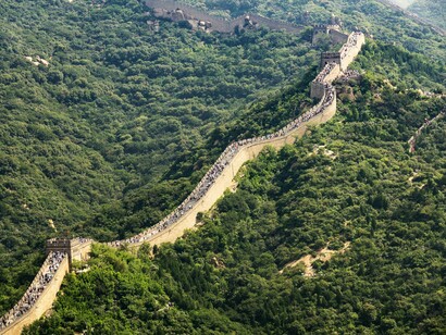 Trecho da Muralha da China serpenteia pelas montanhas em meio à paisagem natural. Construída ao longo de séculos, a estrutura permanece como símbolo da capacidade organizacional do país