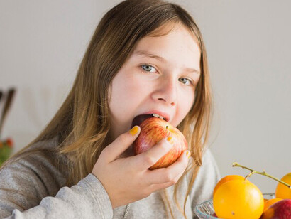 Happy young girl proudly holding healthy food while grocery shopping