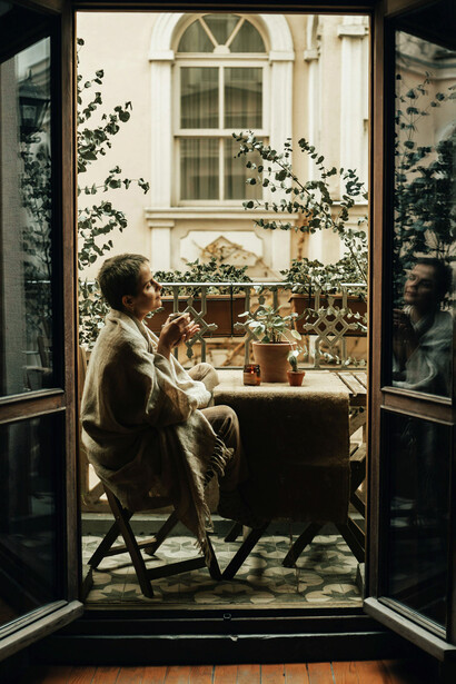 Mujer admirando la ciudad desde un balcón. Balconear es una práctica argentina muy arraigada