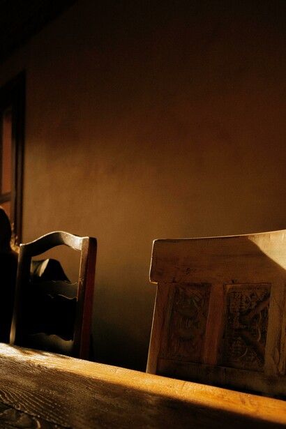 Sillas y una mesa de madera iluminadas por el sol