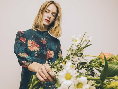 Mulher posa com vestido floral. O floral é um clássico que nunca "saiu de moda"