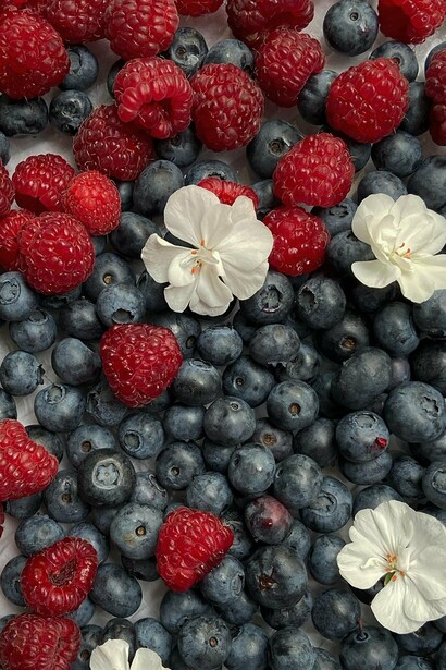 A mix of blueberries and strawberries with flowers