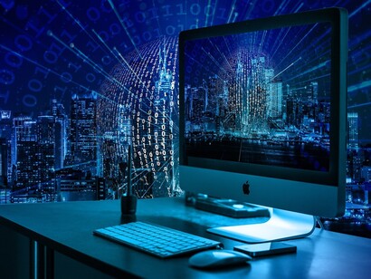 Vista di una città e di un computer con un codice in filigrana: "Alcuni sostengono che stiamo finendo l'era della preistoria, cioè l'era in cui il soddisfacimento dei bisogni e la sopravvivenza erano in stretta relazione alla mano e non al cervello"