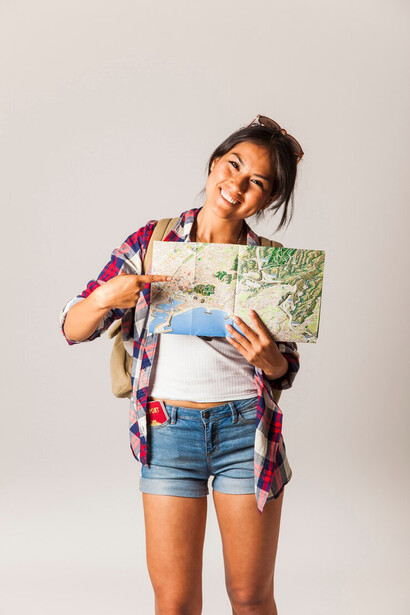 A woman holds a map in her hands, scanning its details with curiosity as she plans her next adventure