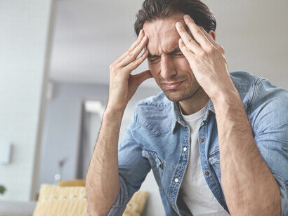 A young man sits alone at home, grappling with feelings of depression, anxiety, and stress