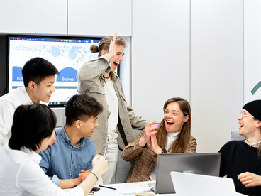 A collaborative team gathered around solutions, representing the power of humane and supportive workplaces