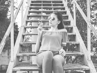 A woman sitting on steps enjoying her cigarette break
