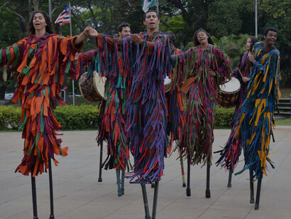 Each stilt walker moves with precision and grace, their strikingly colourful garments fluttering with every step, turning heads and capturing hearts