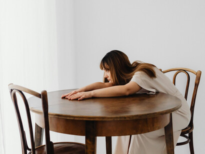 Leaning on a table, a woman appears overwhelmed, absorbed in heavy thoughts