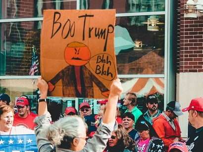 Demonstrators raising signs that reject hatred, division, and Trump’s leadership, symbolizing the struggle to preserve trust, stability, and democratic values