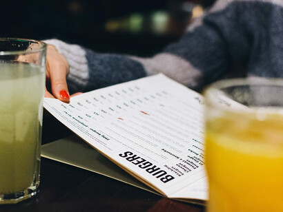 People seated at a bar flipping through an extensive menu, unsure of what to order amid overwhelming choices