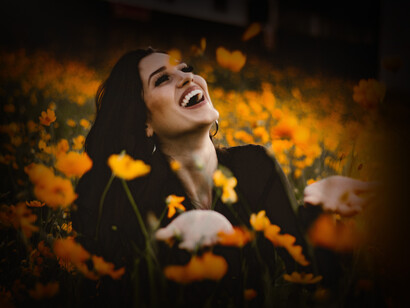 Mujer sonríe con entusiasmo en medio de una pradera. Que tu vida en este año nuevo, sea un poema hermoso y sincero que refleje tu alma