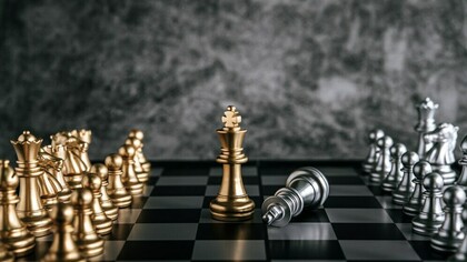 Gold and silver chess pieces on a chessboard symbolizing leadership in business